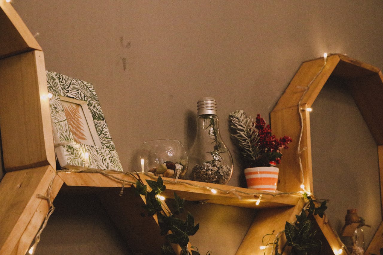 Warm and cozy wooden shelf decorated with plants, lights, and framed art, perfect for home decor inspiration.