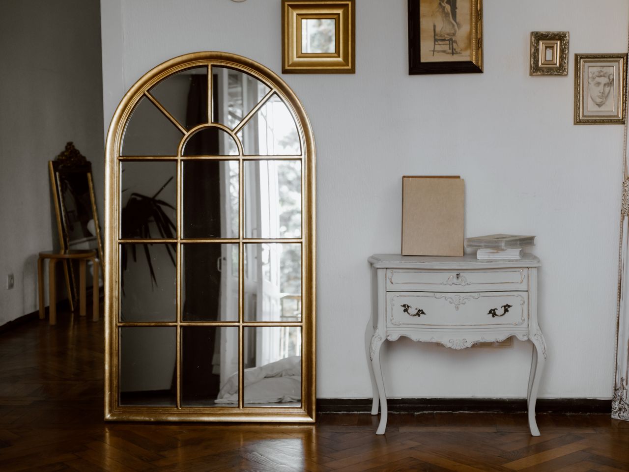 our-story Vintage-style interior featuring a gold arched mirror and a classic white console table.