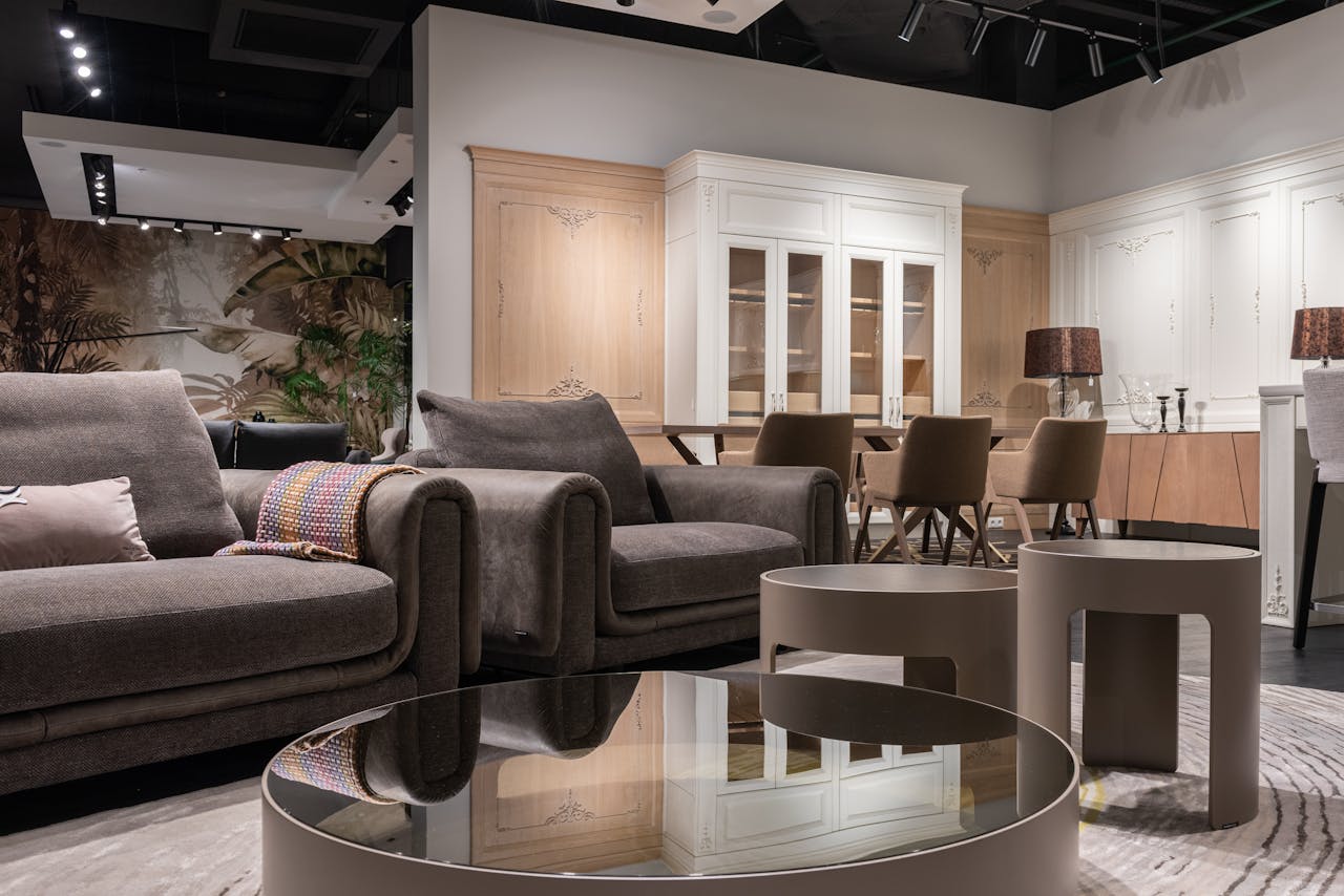 Comfortable sofa and armchair placed near round tables near chairs at dining table at cupboards with decorations in spacious room